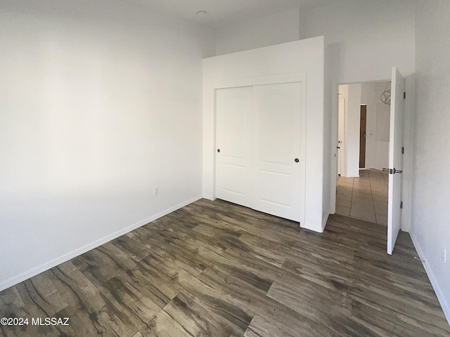 unfurnished bedroom with dark hardwood / wood-style floors and a closet