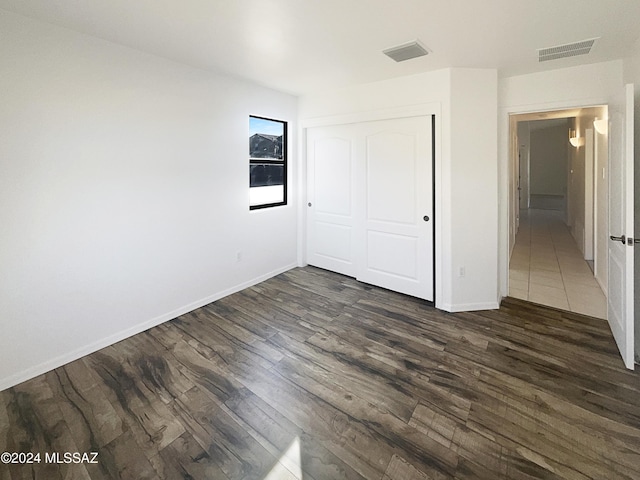 unfurnished bedroom with dark hardwood / wood-style floors and a closet