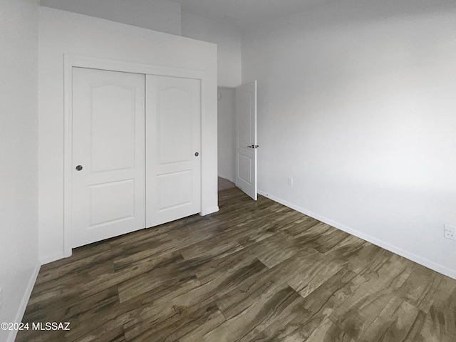 unfurnished bedroom featuring dark hardwood / wood-style floors and a closet