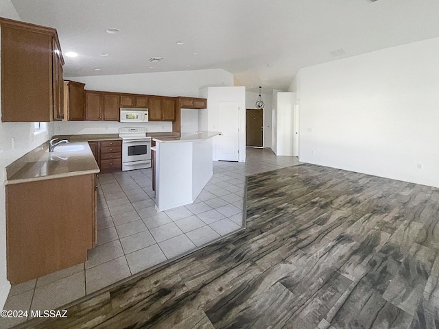 kitchen with a center island, sink, vaulted ceiling, white appliances, and light tile patterned floors