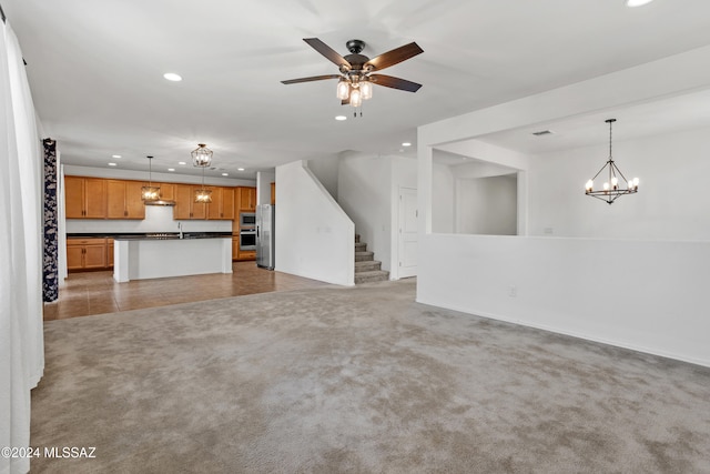 unfurnished living room featuring sink, light colored carpet, and ceiling fan with notable chandelier