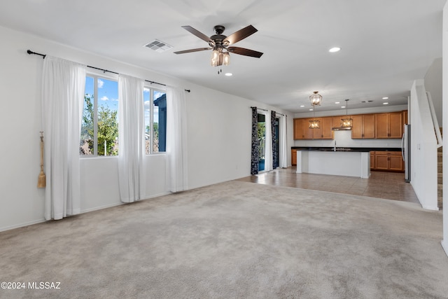 unfurnished living room featuring ceiling fan, sink, and light colored carpet