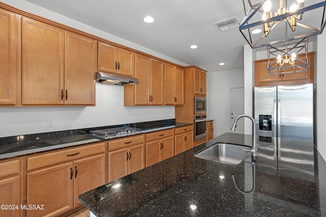 kitchen with sink, stainless steel appliances, a notable chandelier, dark stone countertops, and decorative light fixtures