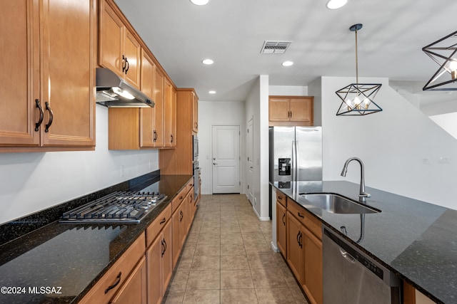 kitchen featuring dark stone countertops, sink, hanging light fixtures, and appliances with stainless steel finishes