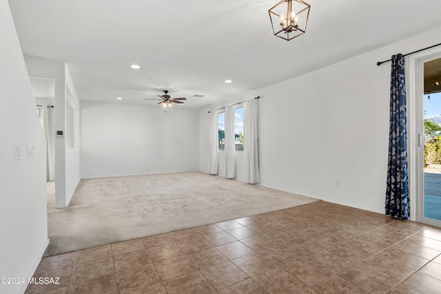 carpeted empty room featuring ceiling fan with notable chandelier