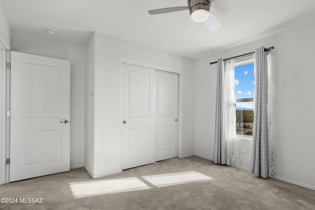 unfurnished bedroom featuring ceiling fan, a closet, and light carpet