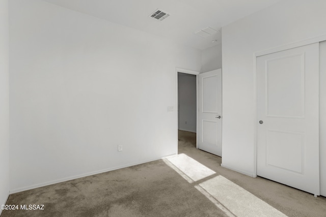 unfurnished bedroom featuring a closet and light colored carpet