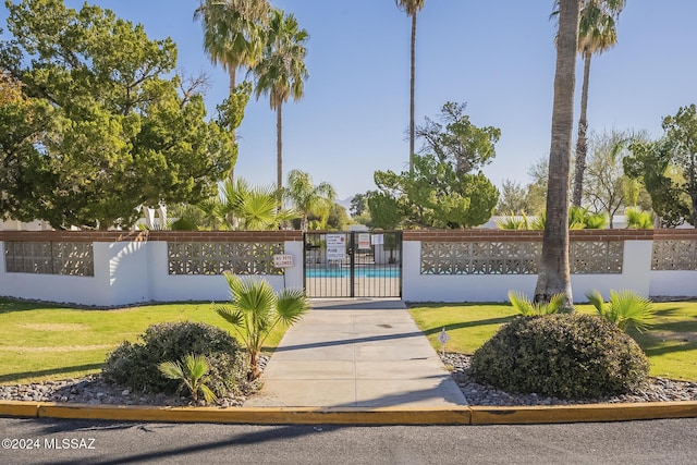 view of gate with a yard and a community pool