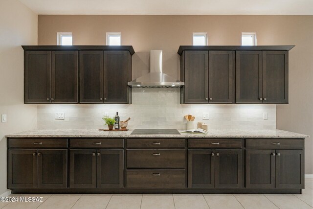 kitchen with backsplash, dark brown cabinets, black electric cooktop, wall chimney range hood, and light tile patterned flooring