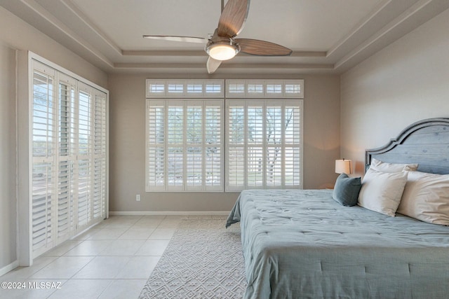 bedroom featuring ceiling fan, light tile patterned flooring, and a raised ceiling