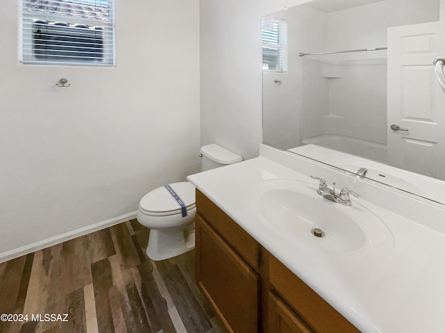 bathroom featuring wood-type flooring, vanity, toilet, and walk in shower