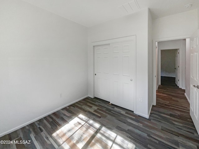 unfurnished bedroom with a closet and dark wood-type flooring