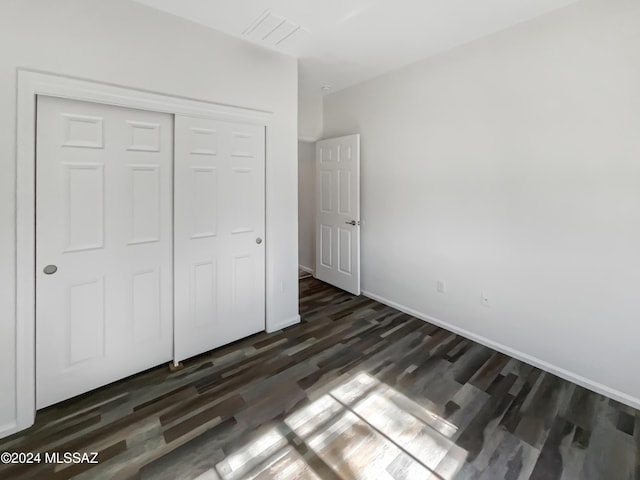 unfurnished bedroom featuring a closet and dark wood-type flooring