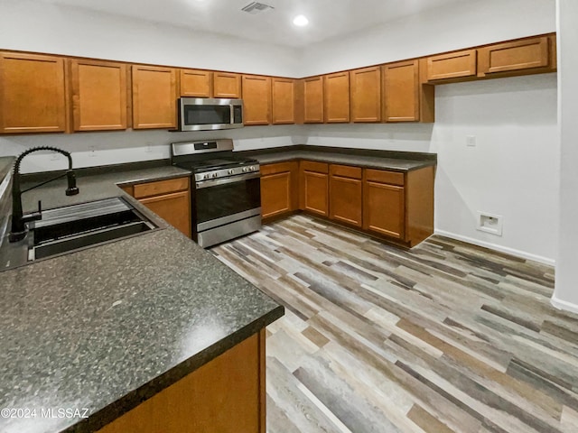 kitchen with sink, stainless steel appliances, and light hardwood / wood-style flooring