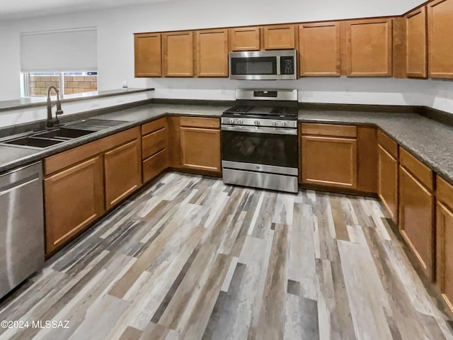 kitchen featuring appliances with stainless steel finishes, light hardwood / wood-style flooring, and sink