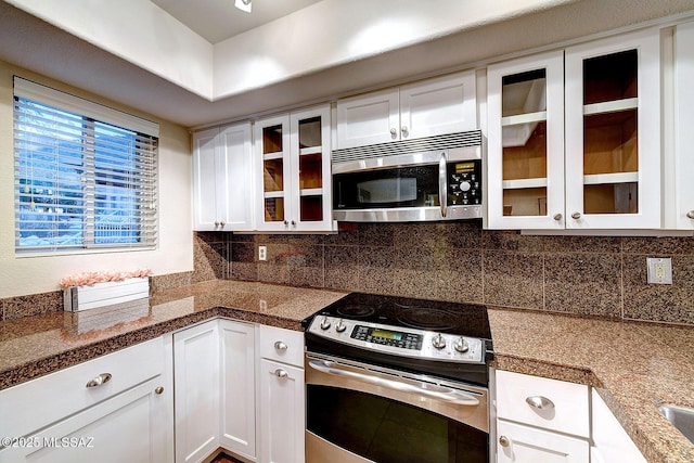 kitchen with dark stone countertops, white cabinetry, backsplash, and appliances with stainless steel finishes