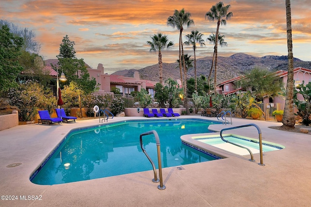 pool at dusk featuring a patio area and a mountain view