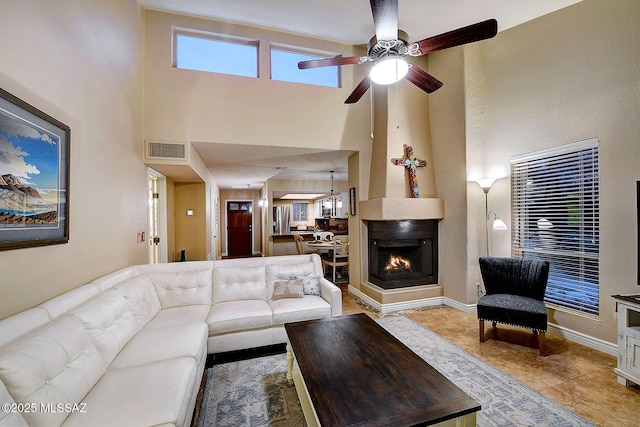 living room featuring a multi sided fireplace, a high ceiling, light tile patterned floors, and ceiling fan