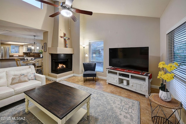 living room featuring a multi sided fireplace, high vaulted ceiling, and ceiling fan