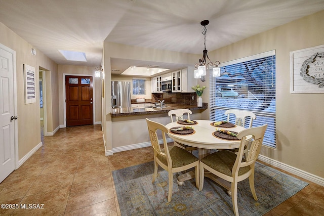 dining space with light tile patterned floors, a skylight, a notable chandelier, and sink