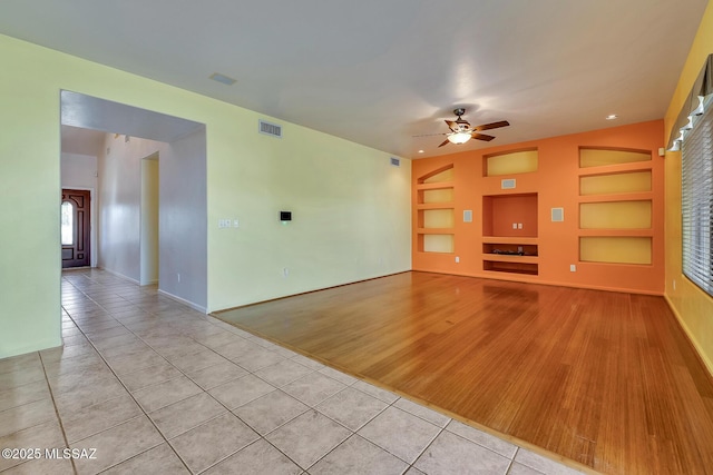 unfurnished living room featuring light tile patterned floors, built in features, and ceiling fan