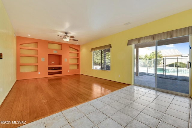 unfurnished living room featuring ceiling fan, built in features, and light tile patterned floors