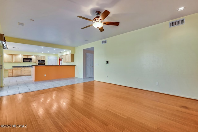 unfurnished living room featuring ceiling fan and light wood-type flooring