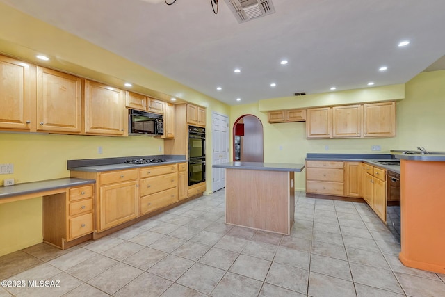 kitchen featuring light brown cabinetry, a kitchen island, black appliances, and light tile patterned floors