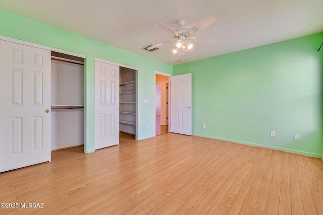 unfurnished bedroom featuring ceiling fan, light hardwood / wood-style floors, and multiple closets