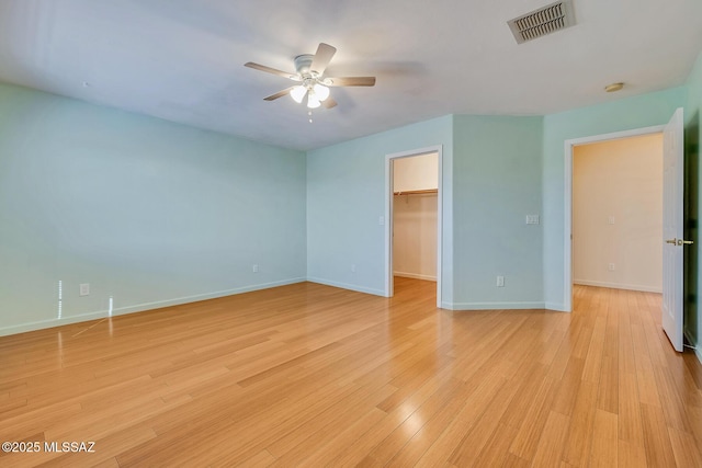 interior space with ceiling fan, a walk in closet, light hardwood / wood-style flooring, and a closet