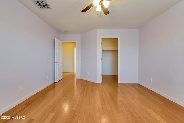 unfurnished bedroom with ceiling fan, light hardwood / wood-style floors, a spacious closet, and a closet