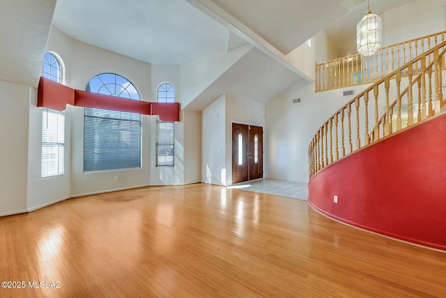 entrance foyer featuring light hardwood / wood-style flooring, a towering ceiling, and a chandelier