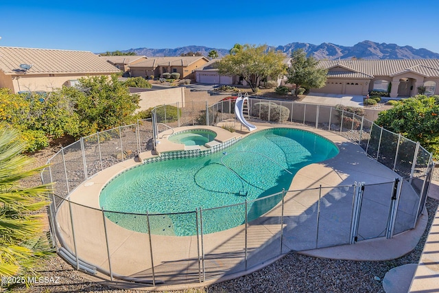 view of pool with a mountain view, a water slide, and an in ground hot tub