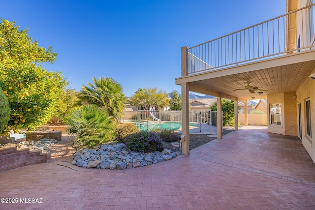 view of patio with a fenced in pool, ceiling fan, and a balcony