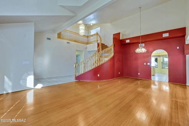 unfurnished living room with beamed ceiling, hardwood / wood-style flooring, and high vaulted ceiling