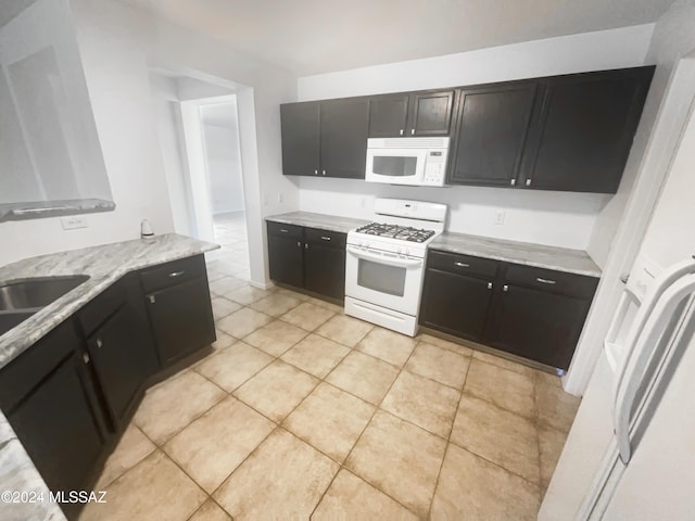 kitchen featuring light stone counters, sink, light tile patterned flooring, and white appliances