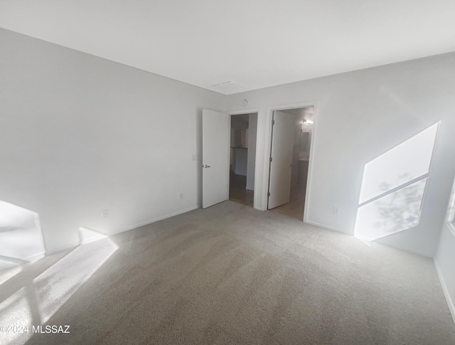 unfurnished bedroom featuring carpet flooring and ensuite bathroom