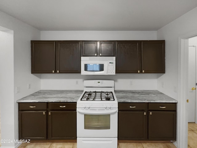 kitchen featuring dark brown cabinetry and white appliances