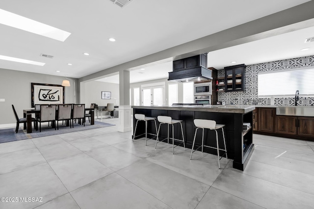 kitchen with sink, a breakfast bar, appliances with stainless steel finishes, backsplash, and a kitchen island