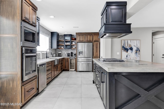 kitchen featuring appliances with stainless steel finishes, beverage cooler, decorative backsplash, custom exhaust hood, and dark brown cabinets