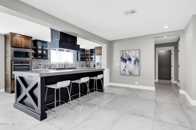 kitchen with sink, a kitchen bar, decorative backsplash, a center island, and stainless steel appliances