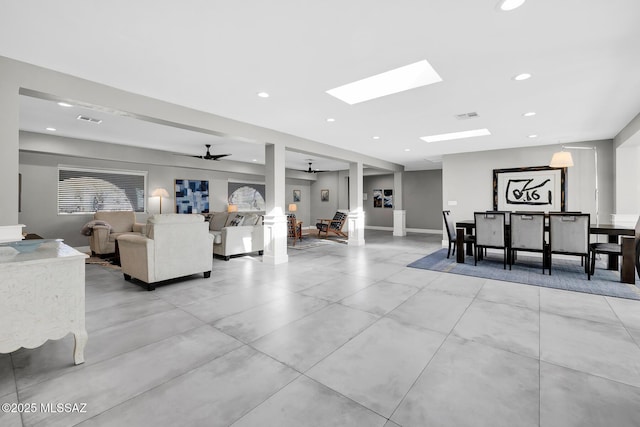 living room featuring ceiling fan and a skylight