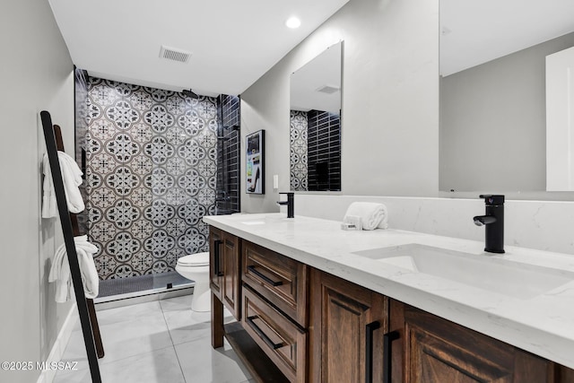 bathroom with tile patterned floors, vanity, toilet, and a tile shower