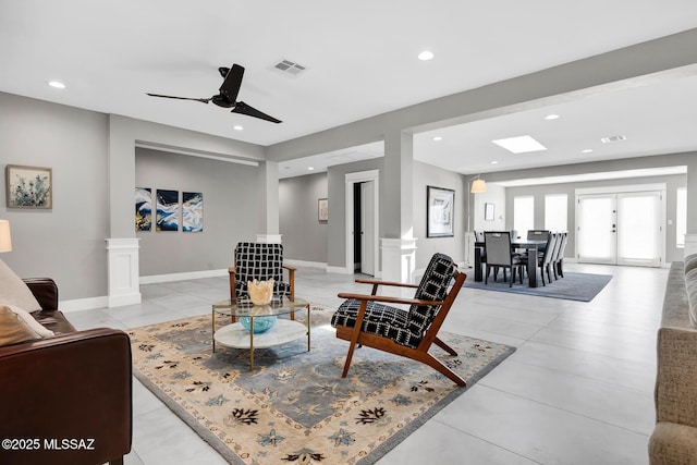 tiled living room featuring ceiling fan and ornate columns