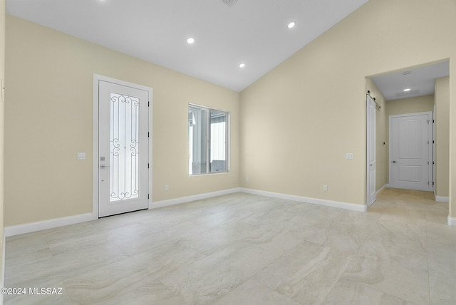 foyer entrance with a barn door and lofted ceiling