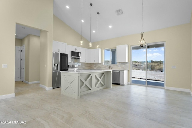 kitchen with a center island, high vaulted ceiling, pendant lighting, white cabinets, and appliances with stainless steel finishes