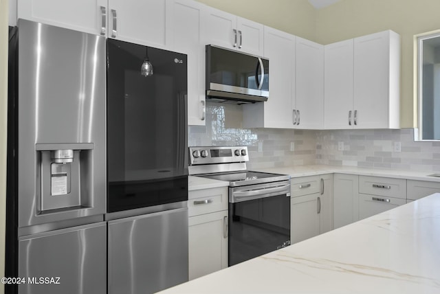 kitchen featuring white cabinets, appliances with stainless steel finishes, decorative backsplash, and light stone counters