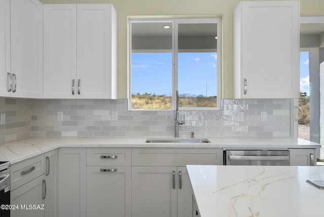 kitchen featuring tasteful backsplash, dishwasher, white cabinets, and sink