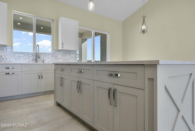 kitchen featuring decorative backsplash, plenty of natural light, hanging light fixtures, and sink