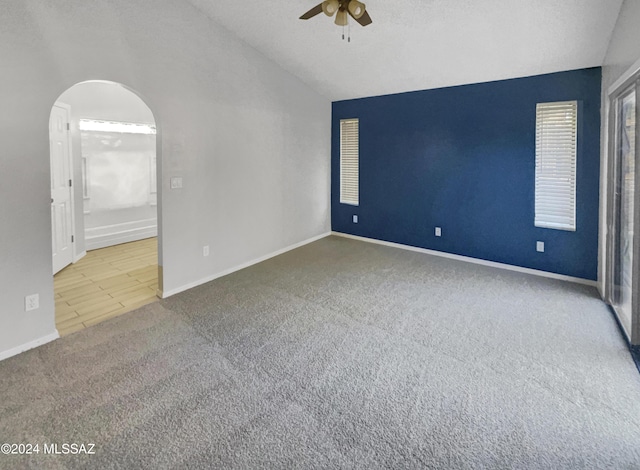 empty room featuring a textured ceiling, ceiling fan, carpet, and lofted ceiling